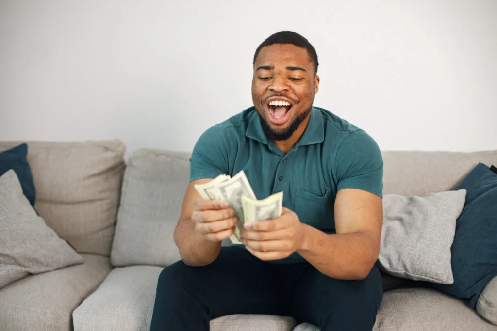 Homem sorrindo enquanto segura notas de dinheiro, simbolizando prosperidade.