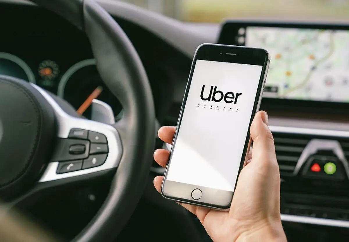 Imagem de um celular mostrando o logo da Uber dentro de um carro, destacando a interface do aplicativo.