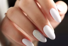 Unhas de esmalte branco com um toque de brilho prateado, destacando elegância e estilo.