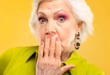 Mulher idosa estilosa com unhas decoradas e expressão surpresa