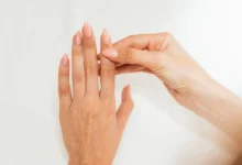 Mãos femininas cuidadas com unhas longas e esmalte nude em fundo branco