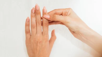 Mãos femininas cuidadas com unhas longas e esmalte nude em fundo branco
