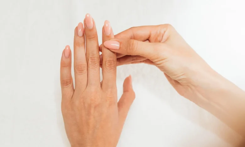 Mãos femininas cuidadas com unhas longas e esmalte nude em fundo branco