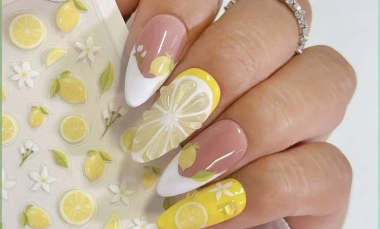 Unhas de porcelana decoradas com desenhos de limões e flores, com detalhes em tons de amarelo e branco.