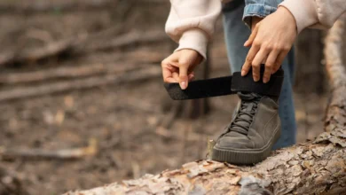 Pessoa ajustando o velcro de um tênis em um cenário natural, como uma solução para tênis com velcro desgastado.