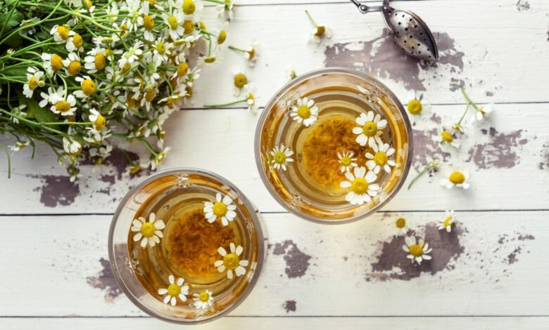 Xícaras de chá de camomila com flores naturais sobre mesa de madeira