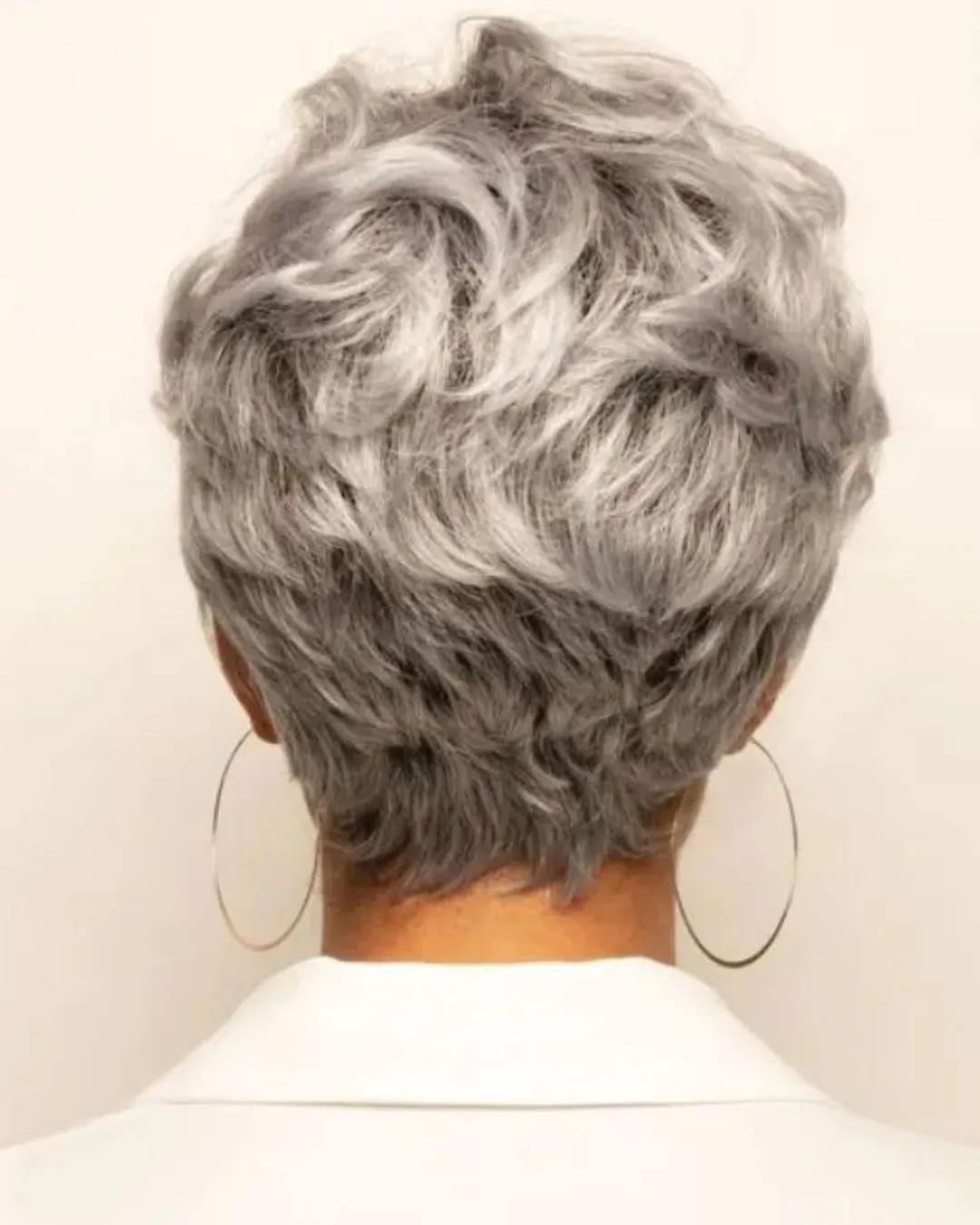 Vista traseira de corte de cabelo curto e cacheado em mulher com fios grisalhos.