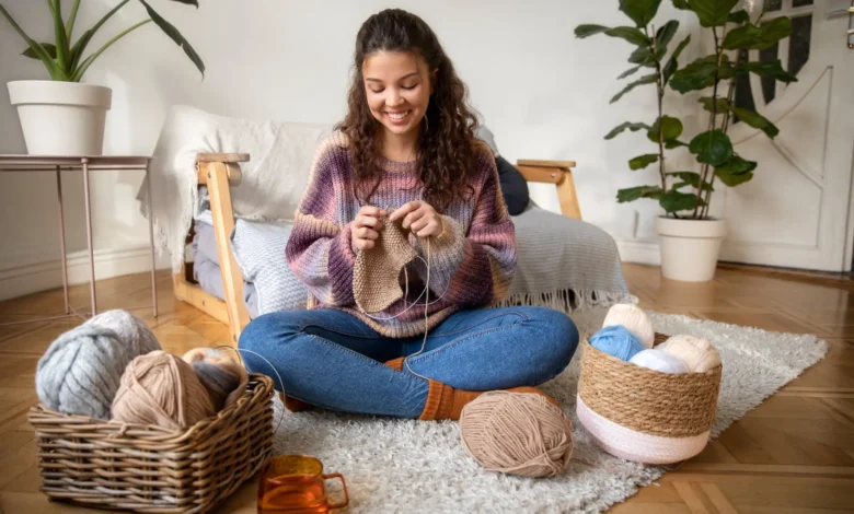 Mulher feliz tricotando em casa, destacando a tendência do crochê que está ganhando popularidade globalmente.