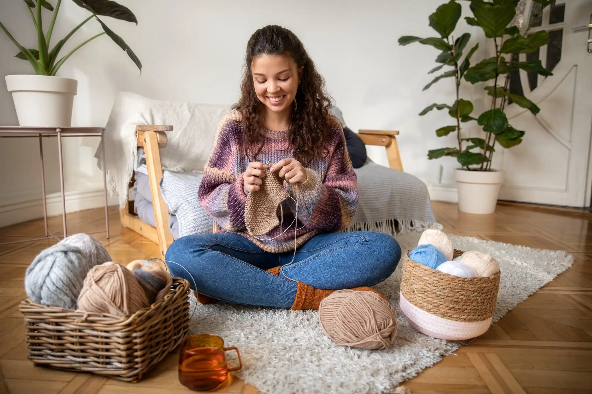 Mulher feliz tricotando em casa, destacando a tendência do crochê que está ganhando popularidade globalmente.