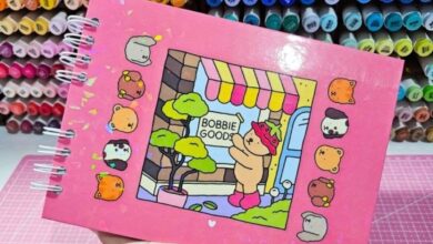 Caderno com ilustração de canetinhas Bobbie Goods e personagem com fantasia de morango, ilustrando um cenário de loja.