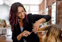Cabeleireira fazendo corte em V em cabelo loiro com luzes