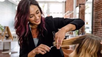 Cabeleireira fazendo corte em V em cabelo loiro com luzes