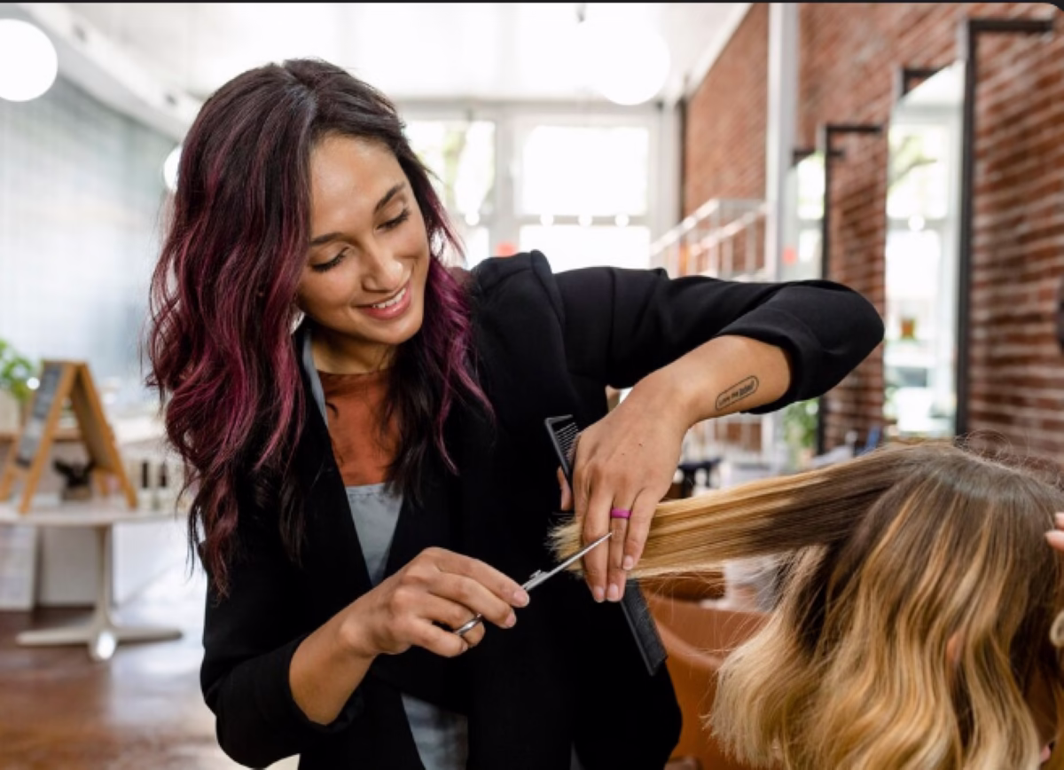 Cabeleireira fazendo corte em V em cabelo loiro com luzes