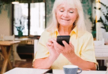 Mulher sorridente enviando mensagem de bom dia pelo celular
