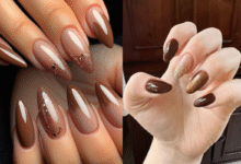 A imagem de uma mão com as unhas pintadas de marrom com glitter dourado.