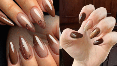 A imagem de uma mão com as unhas pintadas de marrom com glitter dourado.