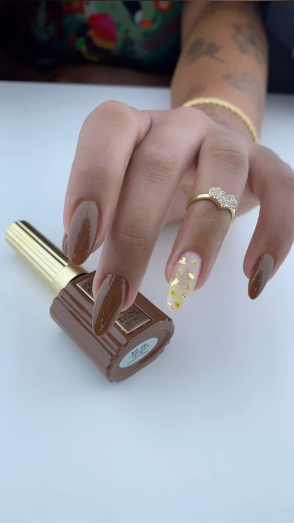 Unhas com esmalte marrom em gel e detalhe dourado floral no anelar