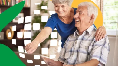 Idosos sorrindo enquanto interagem com um computador, refletindo o impacto positivo da atualização de benefícios do INSS.