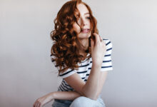 Mulher ruiva com cabelo ondulado e volumoso, representando uma mudança de visual.