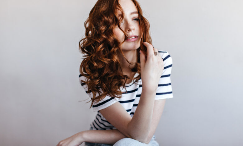 Mulher ruiva com cabelo ondulado e volumoso, representando uma mudança de visual.