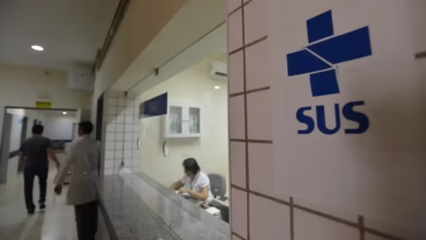 Entrada do atendimento SUS com uma recepcionista no balcão e pessoas na área de espera.