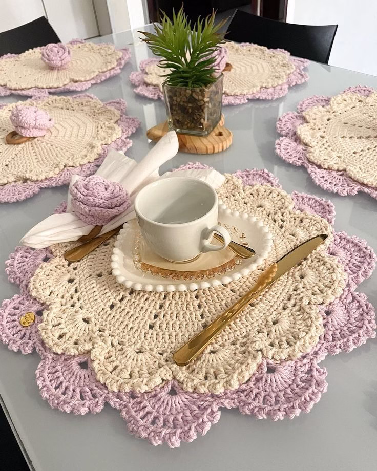 Jogo americano de crochê em tons pastéis lilás e bege, decorado para mesa posta.