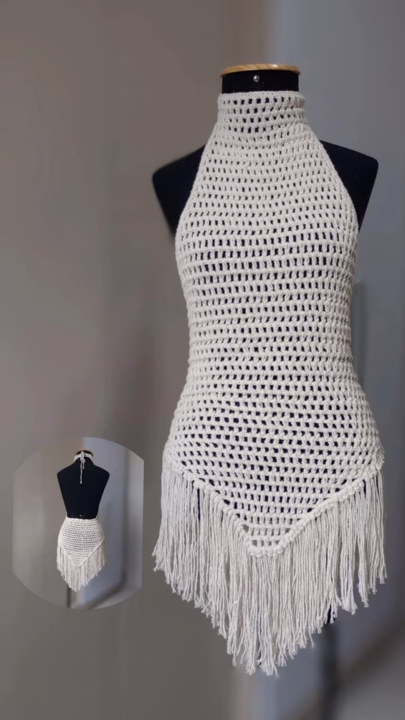 Vestido de crochê branco com franjas longas, estilo boho, ajustado no corpo.