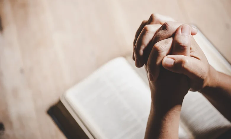 Mãos unidas em oração sobre uma Bíblia Sagrada, refletindo gratidão a Deus por mais um dia.