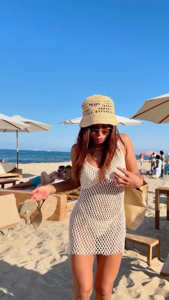 Anitta usando saída de praia em crochê clara na areia da praia