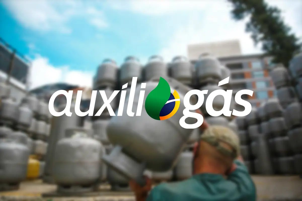 Homem carrega botijão de gás próximo a pilha de cilindros, com o logo do Auxílio Gás em destaque.