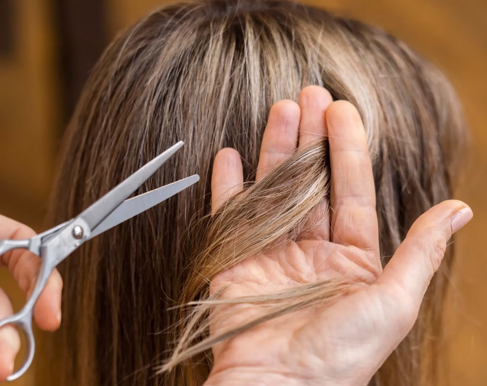 Corte de cabelo sendo feito em mulher com fios longos por profissional de beleza.Corte de cabelo sendo feito em mulher com fios longos por profissional de beleza.