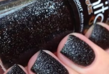 Unhas com esmalte preto brilhante e cintilante, mostrando acabamento elegante e moderno