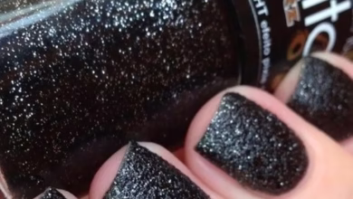 Unhas com esmalte preto brilhante e cintilante, mostrando acabamento elegante e moderno