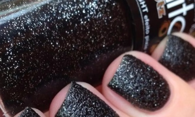 Unhas com esmalte preto brilhante e cintilante, mostrando acabamento elegante e moderno