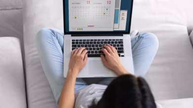 Mulher jovem em seu laptop em casa vendo datas para planejar o feriado prolongado de novembro.