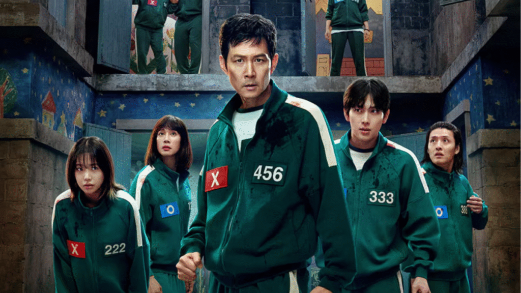 Elenco do dorama "Round 6" usando uniformes verdes e com expressões sérias, em um ambiente misterioso e ameaçador.