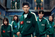 Elenco do dorama "Round 6" usando uniformes verdes e com expressões sérias, em um ambiente misterioso e ameaçador.