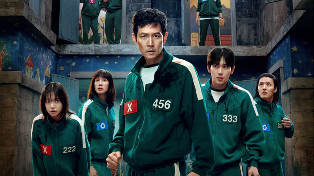 Elenco do dorama "Round 6" usando uniformes verdes e com expressões sérias, em um ambiente misterioso e ameaçador.