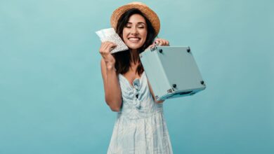 Mulher sorridente segurando ingressos e mala pequena, simbolizando viagem nos feriados prolongados de setembro