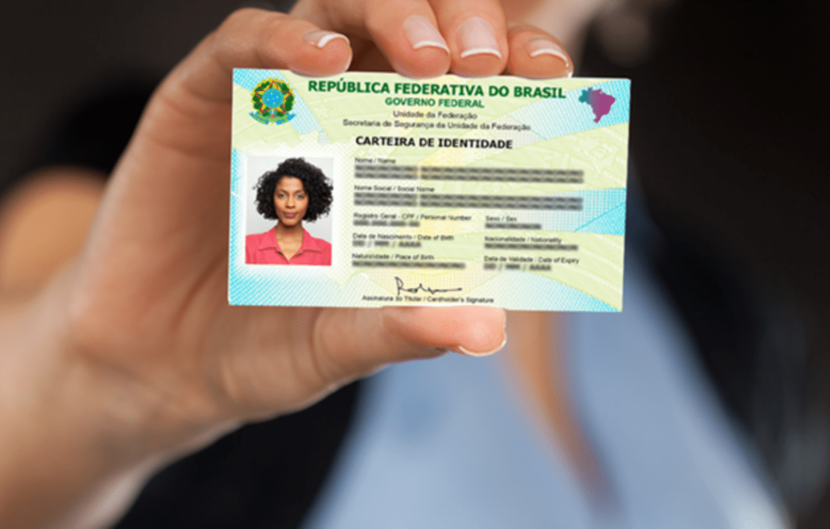 "Imagem de uma pessoa segurando a nova Carteira de Identidade Nacional (CIN) no Brasil, com informações legíveis sobre o documento.