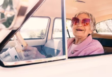 Idosa sorrindo dentro de um carro antigo com óculos de sol, em alguns estados, pessoas com idade superior a 60 ou 65 anos têm direito à isenção do IPVA, desde que preencham os requisitos estabelecidos pela legislação local