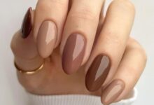 Unhas de manicure sofisticada em tons de marrom, com acabamento brilhante e minimalista.