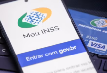 Logo do Meu INSS exibido em um smartphone com cartão de Previdência Social ao fundo.