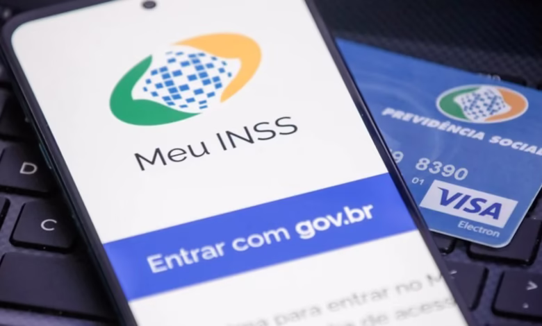 Logo do Meu INSS exibido em um smartphone com cartão de Previdência Social ao fundo.