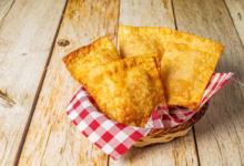Cestinha com pastéis assados dourados sobre toalha xadrez em fundo rústico