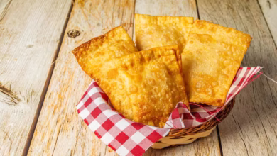 Cestinha com pastéis assados dourados sobre toalha xadrez em fundo rústico