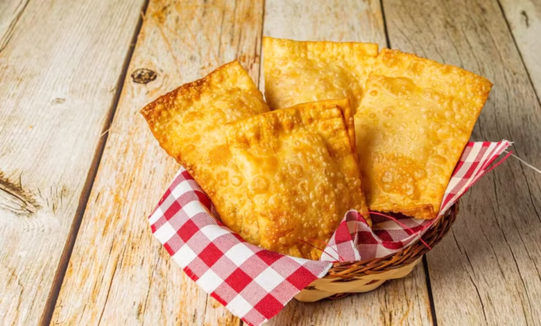 Cestinha com pastéis assados dourados sobre toalha xadrez em fundo rústico