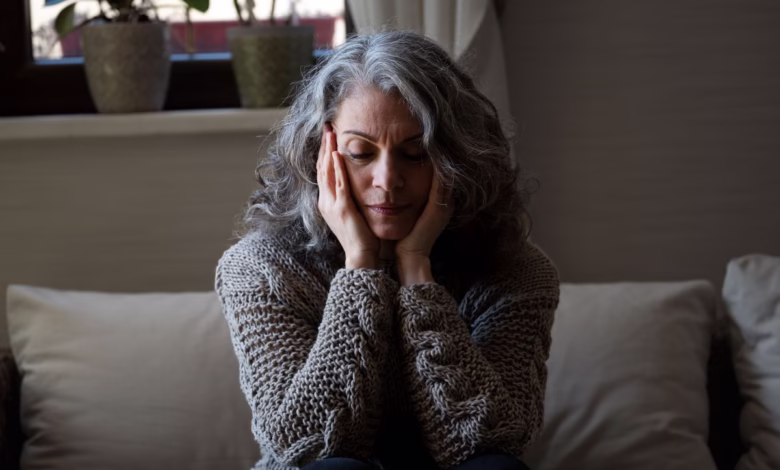Mulher sentada com expressão triste, refletindo sobre os impactos da menopausa na saúde mental