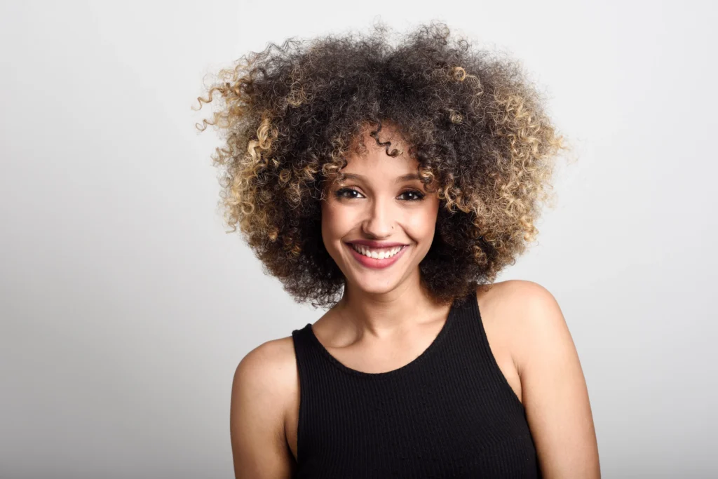 Cabelo natural saudável e brilhante, refletindo os benefícios de menos exposição a químicos e maior autoestima.