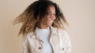 Mulher sorrindo com cabelo cacheado e natural, em movimento, mostrando uma atitude positiva e cheia de confiança.